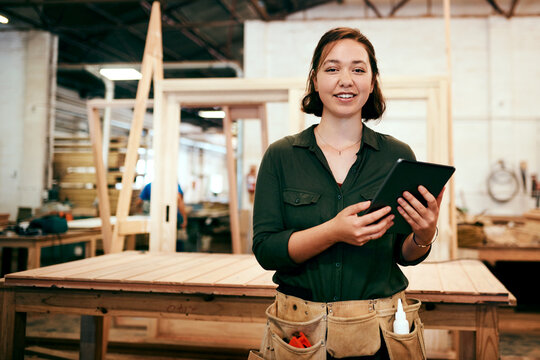 Portrait, smile and tablet with carpenter woman in workshop for craftsmanship, joinery or woodworking. Industry, online order and technology with confident person in warehouse for carpentry or trade