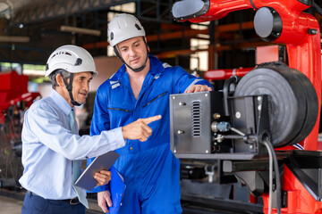 factory workers in maintenance robot machine,senior man expert manager using tablet computer giving advice young male caucasian technician in small industry