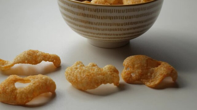 Beaautiful ceramic bowl with pattern on white table containing orange reddish crisps.