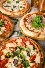 Top view of various neapolitan pizzas on grey stone table