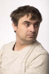 Obraz premium Portrait of a man looking to the side, wearing a light beige shirt. The simple background emphasizes the subject's facial expression, perfect for professional or casual themes.