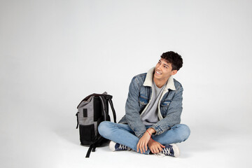Chico estudiante con mochila mirando a un lado y sonriendo. Joven universitario con actitud...