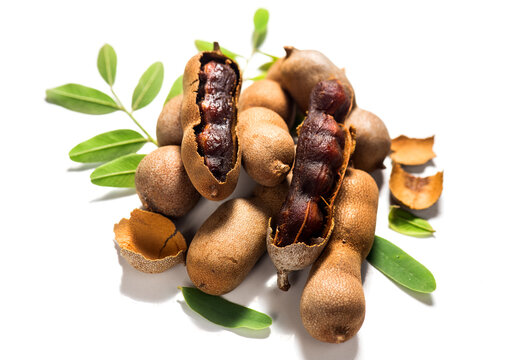 Tamarind tropical fruits isolated on white background. Fresh Tamarind pods with leaves (Tamarindus indica, Indian date), healthy vegan food close up  