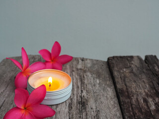 Scented candles with pink frangipani flowers on old wooden table about relaxation and spa    © MothelifeStudio