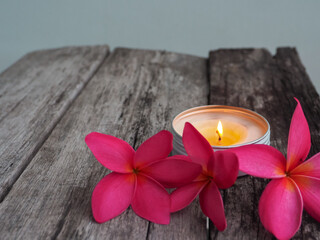 Scented candles with pink frangipani flowers on old wooden table about relaxation and spa    © MothelifeStudio