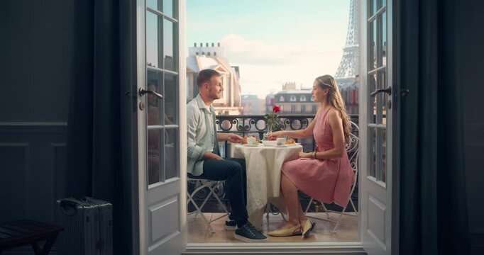 Romantic Scene of a Couple Having Breakfast on a Paris Balcony, Holding Hands as They Eat Croissants and Drink Coffee. The Eiffel Tower Stands Tall in the Background, Making for a Scenic View