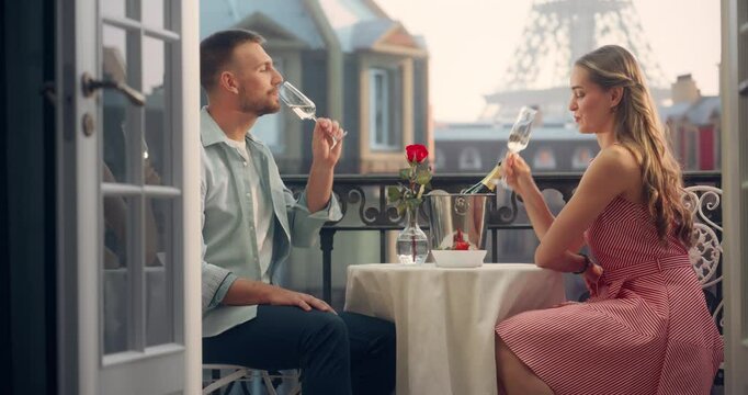 Champagne Glasses Clink in Celebration as a Couple Enjoys a Romantic Evening on a Paris Balcony, They Hold Hands Together. The Eiffel Tower Stands in the Distance, Adding to the Perfect Ambiance
