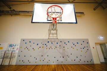Indoor gym with basketball hoop and climbing wall.