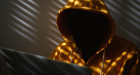 Computer hacker wearing yellow hoodie using laptop