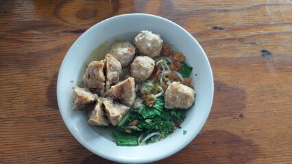 A bowl of delicious Indonesian bakso meatball soup. The soup is filled with tender meatballs, savory broth, and topped with fresh vegetables. Perfect for a warm and satisfying meal.