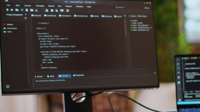 Asian programmer seen typing code for a user interface design on dual monitors, working in a digital workspace. Woman coder working on software engineering and front end development. Camera B.