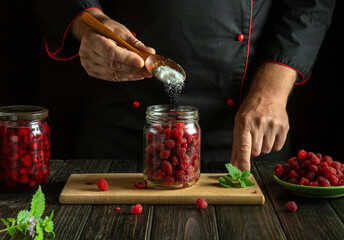 A chef adds a spoonful of sugar to raspberries before making a sweet mors. A low-key concept for making a raspberry drink. © Виталий Борковский