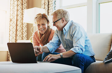 Entertainment for their retirement, sorted. Shot of a mature couple using a laptop together at home on the sofa.