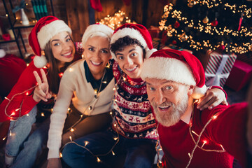 Photo of grandfather father in santa claus hat make selfie family granddaughter do v sign celebrate christmas in house room