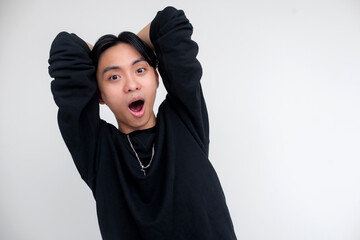 Young asian man displaying an expression of shock and surprise on a white background