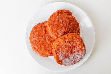 Close-up of three uncooked frozen spicy veggie patties on a white plate, ideal for vegan meal prep concepts