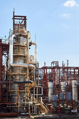 Old distillation column towers and reactors under blue evening sky background at chemical plant. Exterior of silver metal rusty enterprise with copyspace.