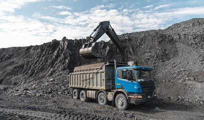 Large quarry dump truck and excavator. Big mining truck work coal deposit. Loading coal into body...
