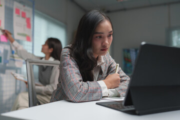 Fototapeta premium Stressed Asian businesswoman having headache in office with laptop financial business online marketing Irritability, tiredness with headaches or fatigue, drowsiness, office syndrome.