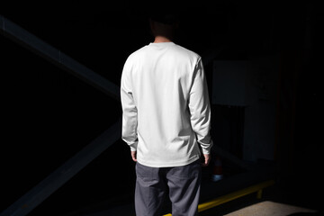 Person in white long sleeved shirt mockup template in an urban outdoor environment, with sharp sunlit shadows. Isolated blank surface to place your design. 