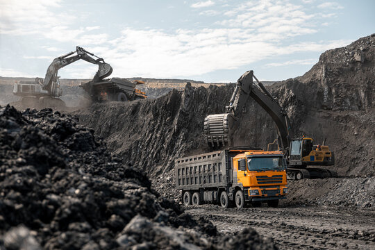 Large quarry dump truck and excavator. Big mining truck work coal deposit. Loading coal into body truck. Production useful minerals. Mining mining machinery to transport coal from open-pit production