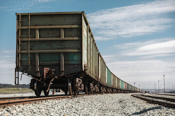 Panorama railroad tracks with wagons and railway transport. View to railway station with railroad tracks with wagons. Loading railway cars. Railway wagons standing at the station waiting for loading