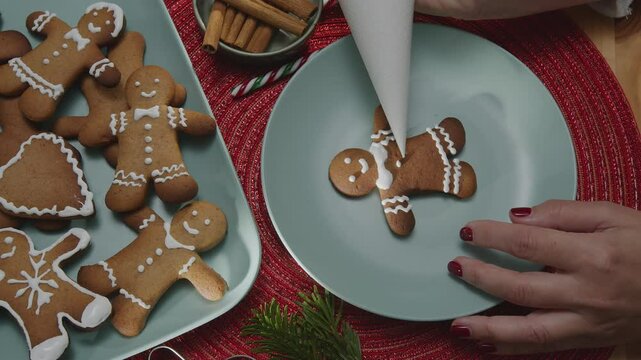 Making Christmas cookies - gingerbread men,  a woman is decorating cookies with royal icing.