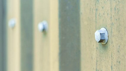 Metal bolts on the exterior surface of a fence.