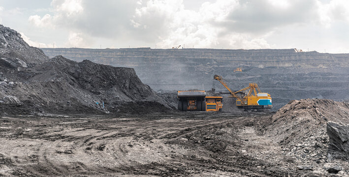 Panoramic view of coal mine. Open pit mine industry, big yellow mining truck for coal quarry. Open coal mining anthracite mining. Pit on coal mining by open way. Rock loading in trucks. Large truck
