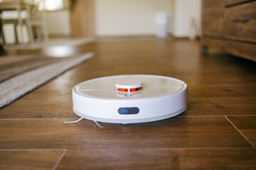Close up of smart gadget working chore and vacuuming floor at home.
