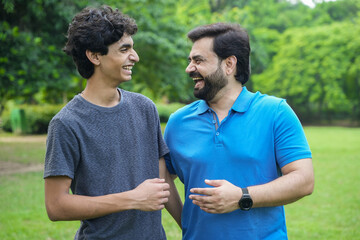 Young indian father and son standing at summer park or garden enjoying time together. Bonding and...