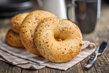 Bagel sprinkled with fried onion, sesame and poppy seeds on wooden table.