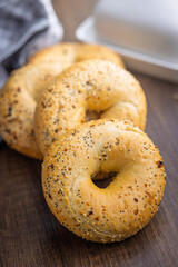 Bagel sprinkled with fried onion, sesame and poppy seeds on wooden table.