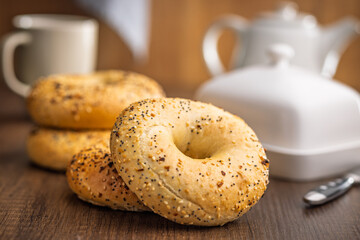 Bagel sprinkled with fried onion, sesame and poppy seeds on wooden table.