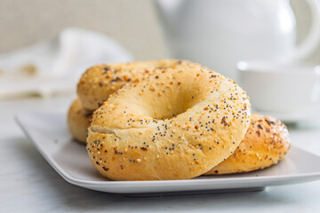 Bagel sprinkled with fried onion, sesame and poppy seeds on plate on kitchen table.
