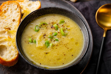A cup of leek soup with toasted bread close up