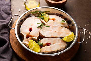 Raw catfish steaks with herbs, lime and spices in a baking dish on a gray background