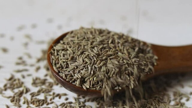 Cumin Seeds or Jeera Falling on a Wooden Spoon
