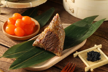 Traditional Chinese rice dumplings placed on a wooden table with beef and egg yolk fillings