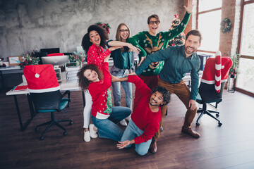 Fototapeta premium Full body photo of cheerful young people colleagues posing team show circle cozy christmas party decor spacious office indoors