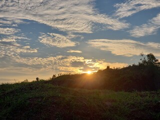 Sunset Over a Grassy Hilltop with a Cloudy Sky