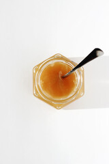 Glass Jar of Natural Honey, with Spoon in, Top View on White Background. Farm Natural Products.