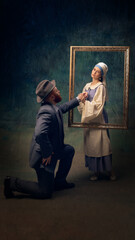 Man kneeling in front of woman, proposing through picture frame. Both dressed in vintage European attire, creating timeless scene of love and devotion. Concept of eras comparison, creative vision, ad