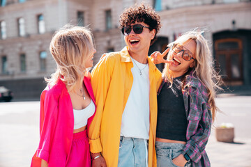 Group of young three stylish friends posing in the street. Fashion man and two cute female dressed...