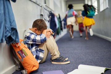Schoolboy crying on floor after suffering an act of bullying