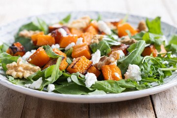 Pumpkin salad with arugula, walnuts and feta cheese on wooden