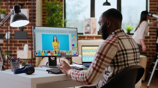 Freelance graphic designer editing photos on a modern computer setup in a remote office. Ideal workspace for a digital design professional, retouching digital pictures from home. Camera B.