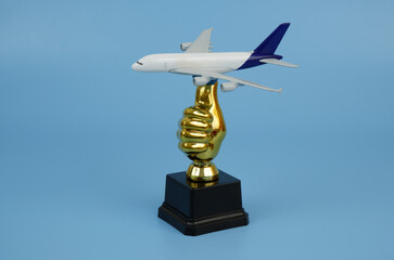 Airplane and thumbs up trophy cup on blue background.	Good price for airplane tickets concept.