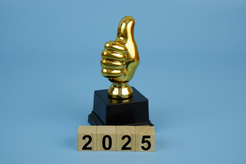 Gold champion thumbs up trophy cup and cubes with numbers 2025 on blue background. Best things in...