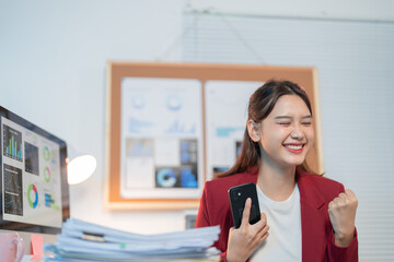 Young businesswoman is working in a modern office, she is very happy and excited about the good...